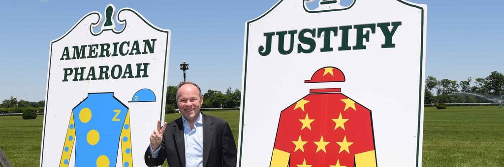 Collmus posing with American Pharoah and ustify's champion signs (Larry Collmus Photo)